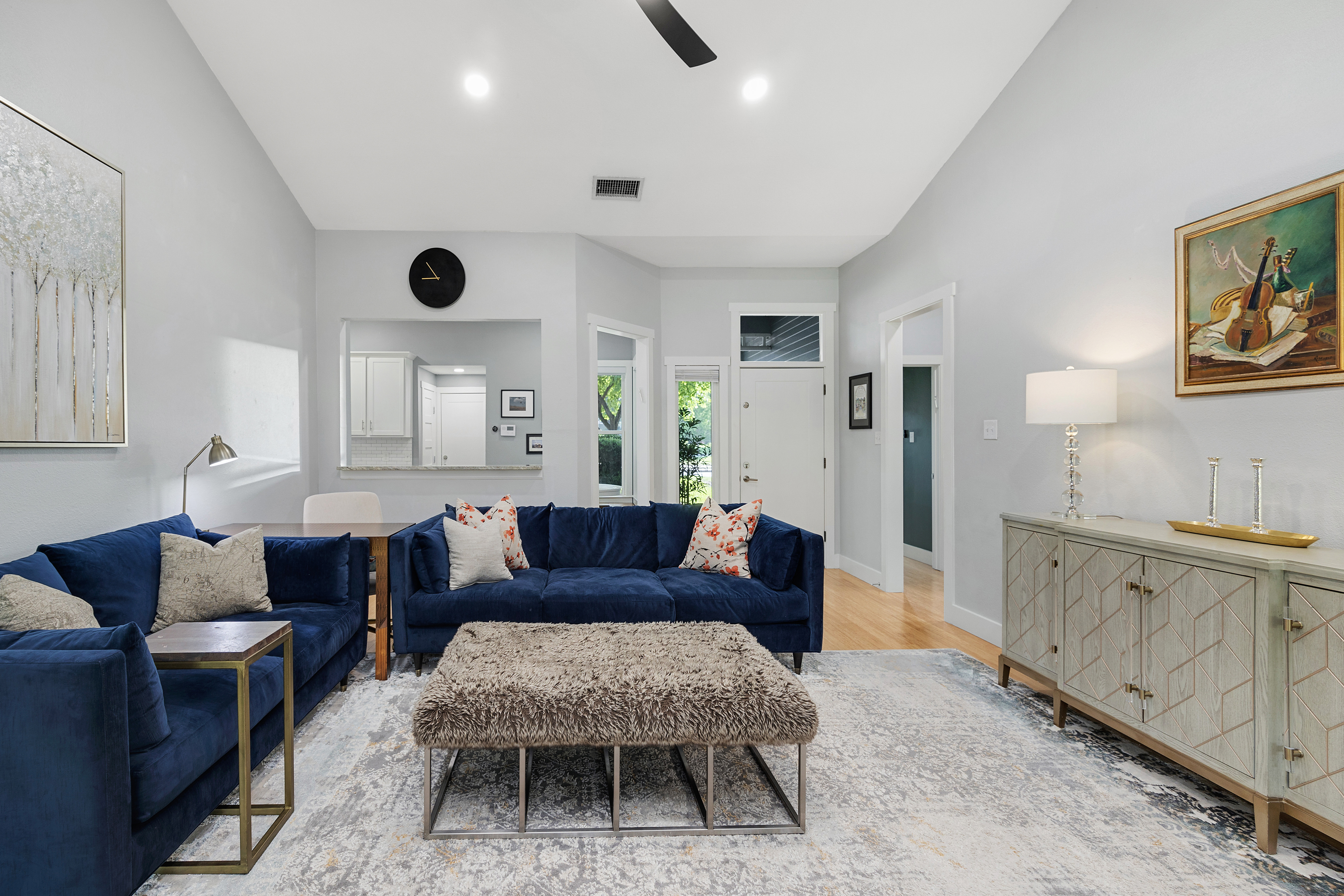 Open-concept living room with a spacious layout and vaulted ceiling, neutral tones, granite fireplace, and modern furniture.