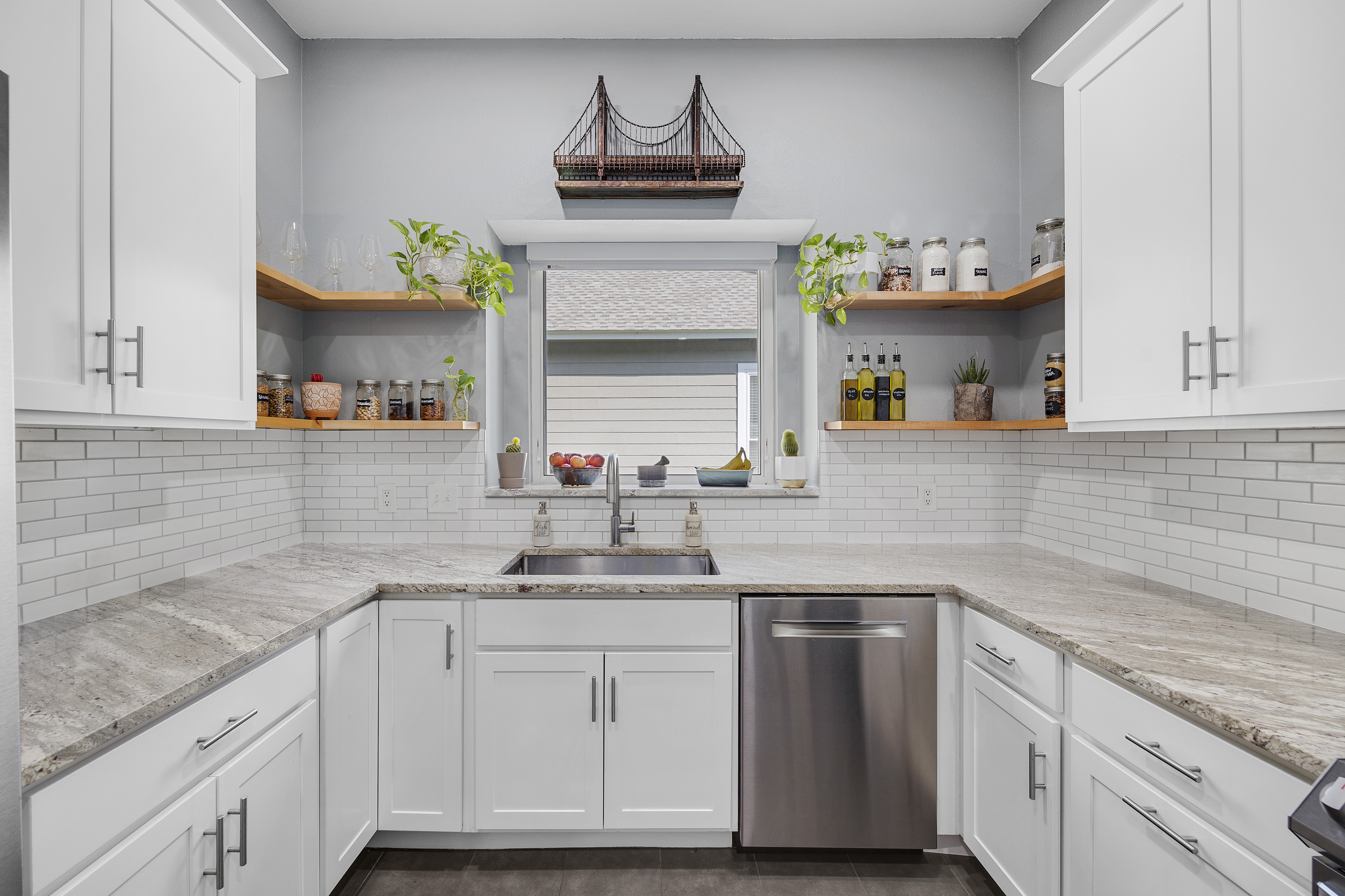 White modern kitchen with granite countertops, shaker cabinets, porcelain tile floors and stainless steel appliances.