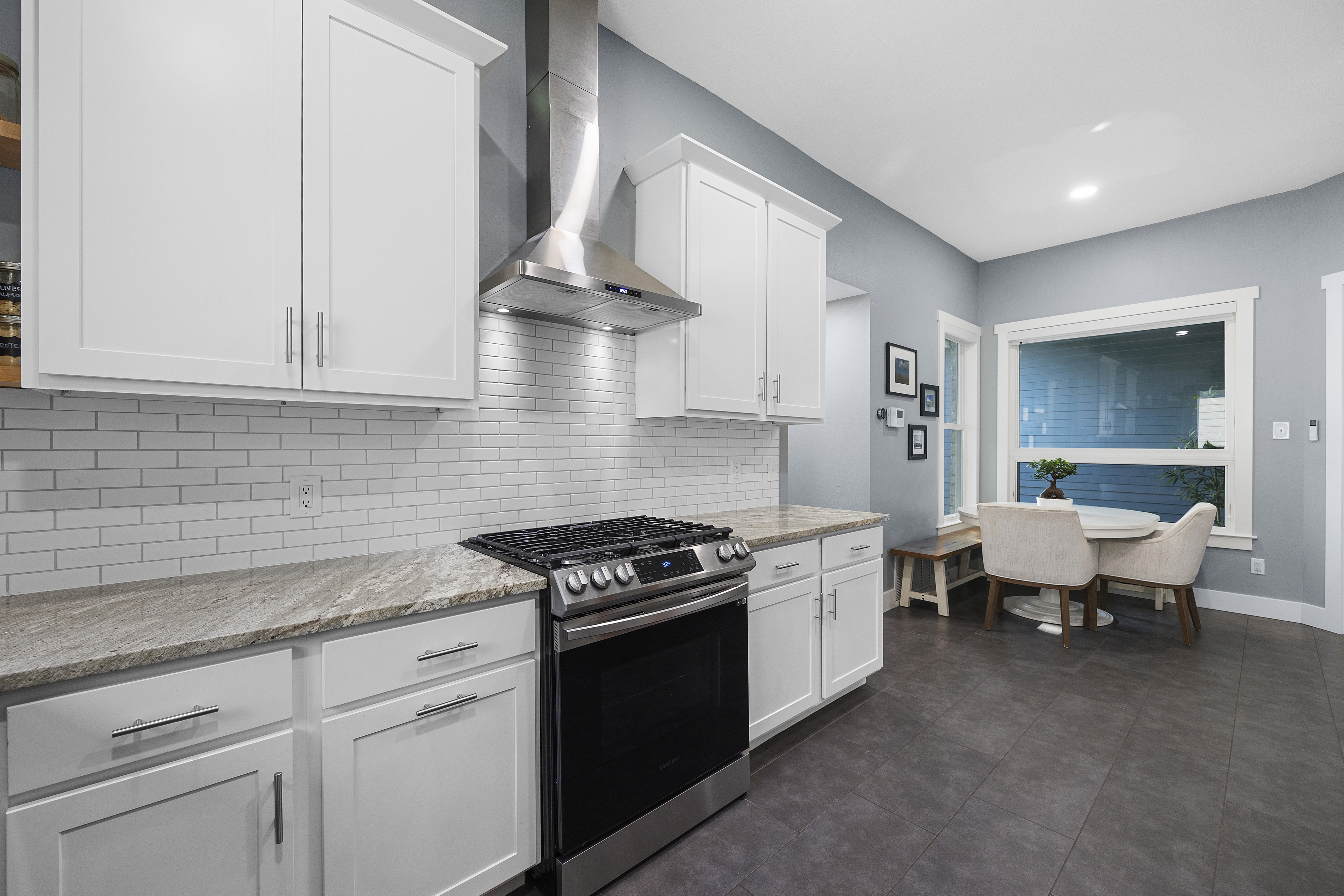 White modern kitchen with granite countertops, shaker cabinets, porcelain tile floors and stainless steel appliances.