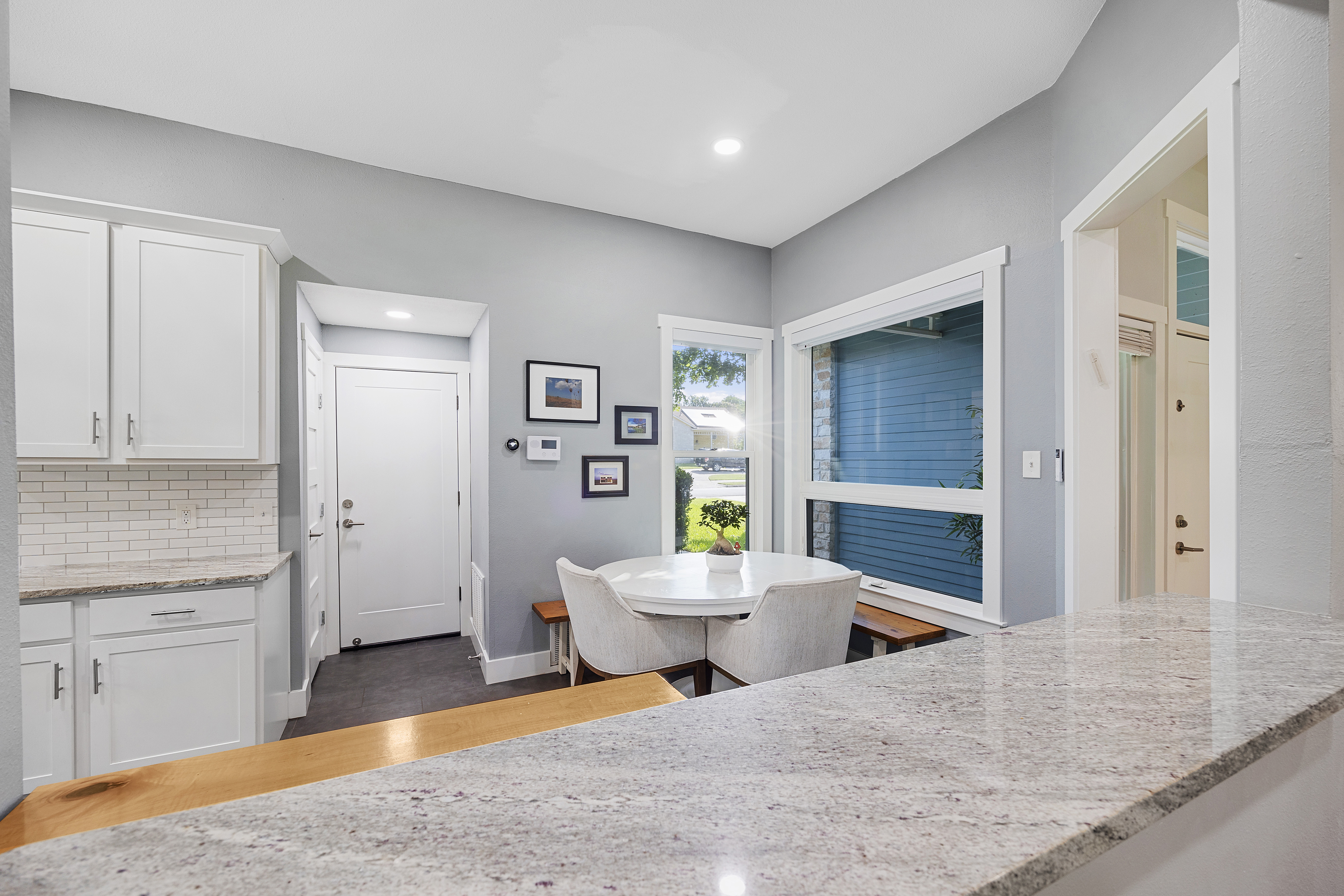 White modern kitchen with granite countertops, shaker cabinets, porcelain tile floors, stainless steel appliances and an eat-in kitchen area.