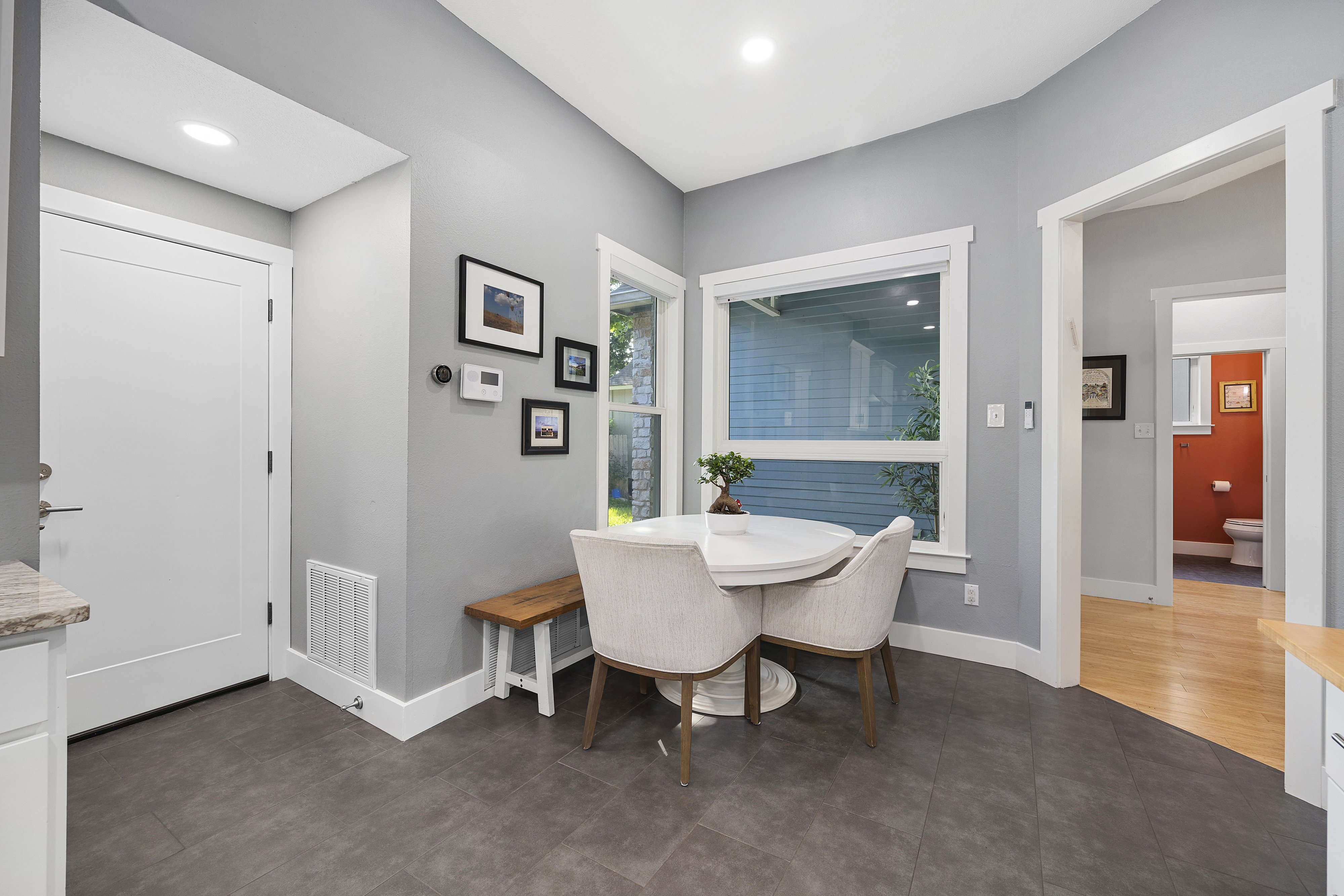 White modern kitchen with granite countertops, shaker cabinets, porcelain tile floors, stainless steel appliances and an eat-in kitchen area.