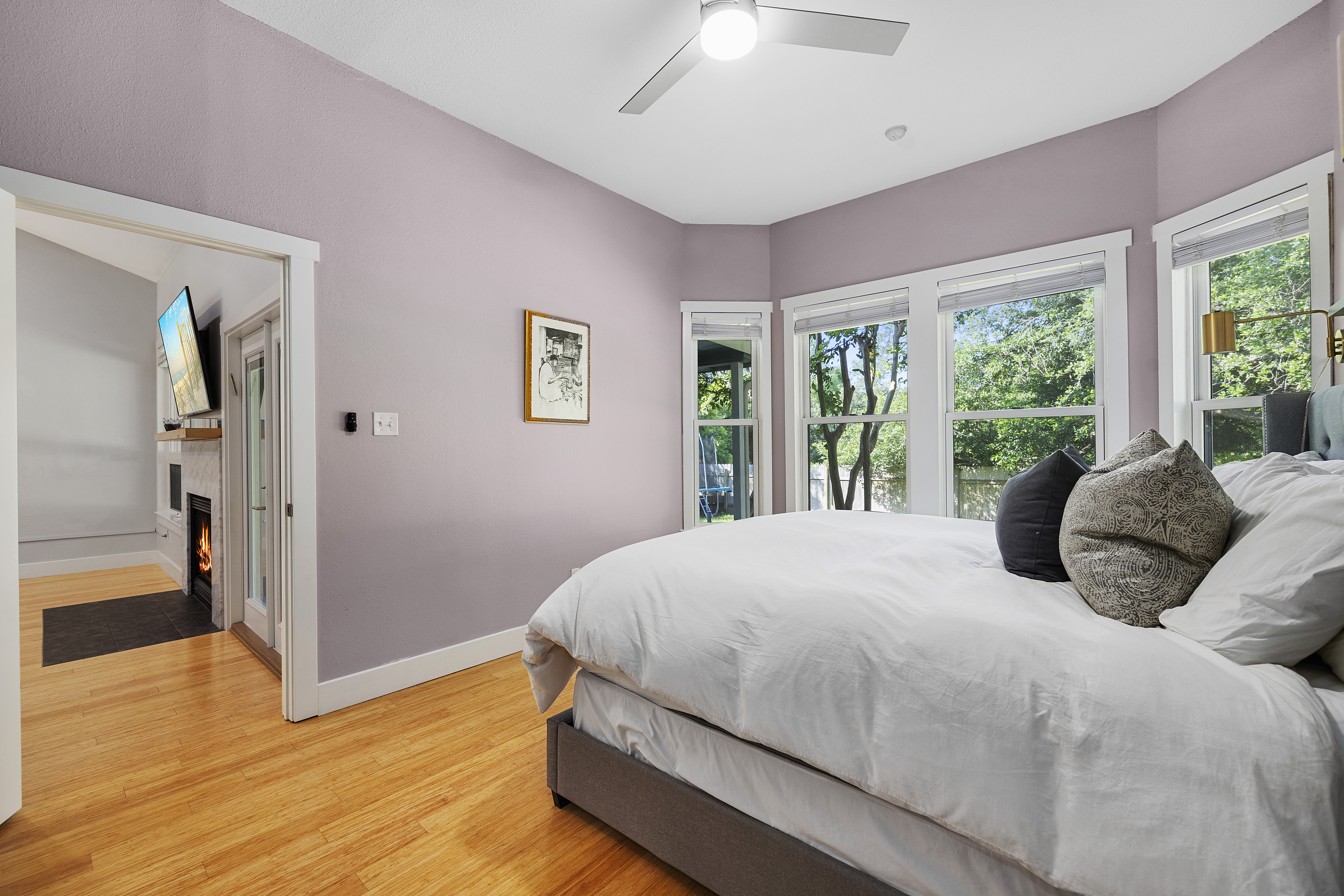 Master bedroom with mauve walls, a spacious layout, a king bed, floating nightstands, window trim, large windows, tall ceilings, and a dresser.