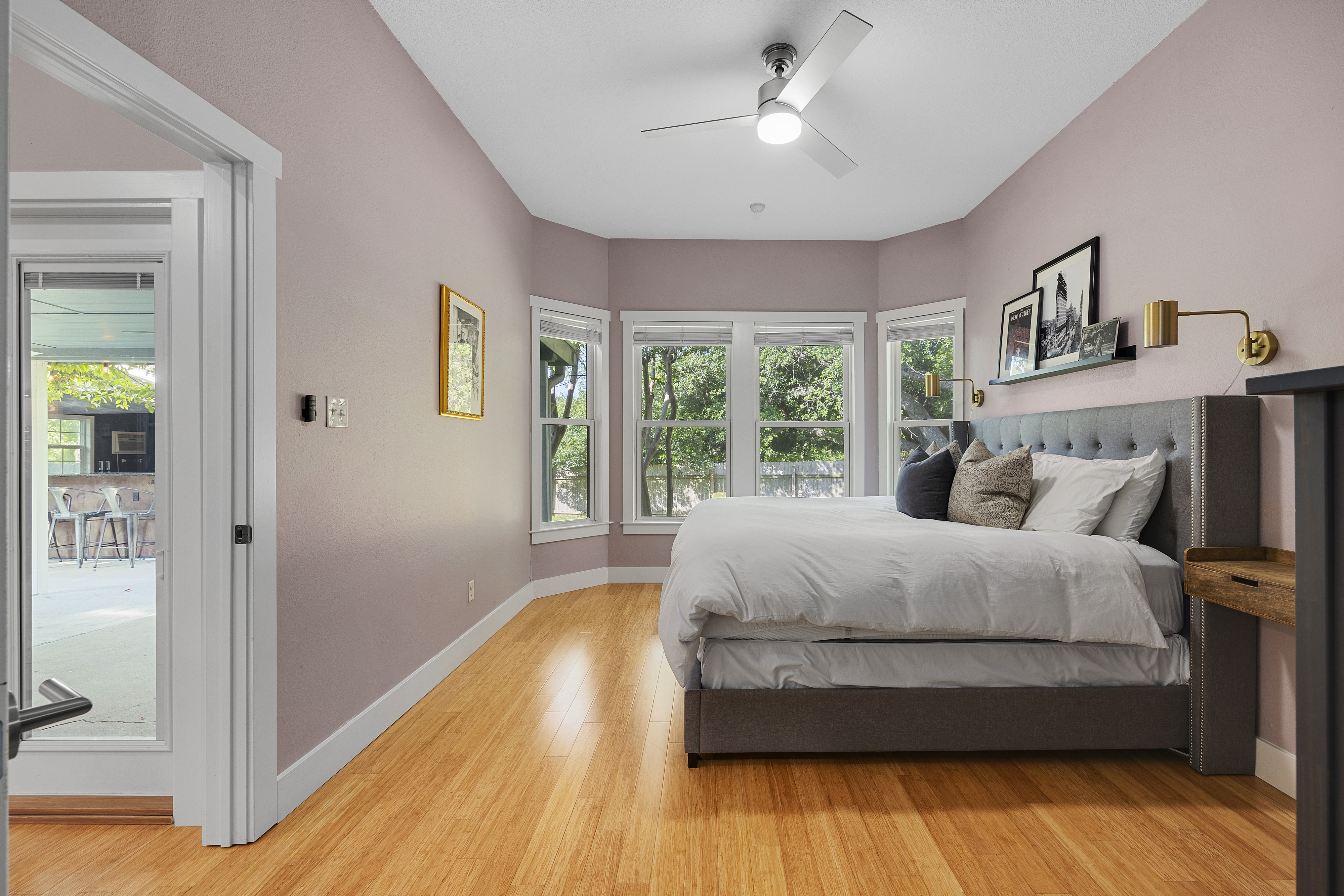 Master bedroom with mauve walls, a spacious layout, a king bed, floating nightstands, window trim, large windows, tall ceilings, and a dresser.